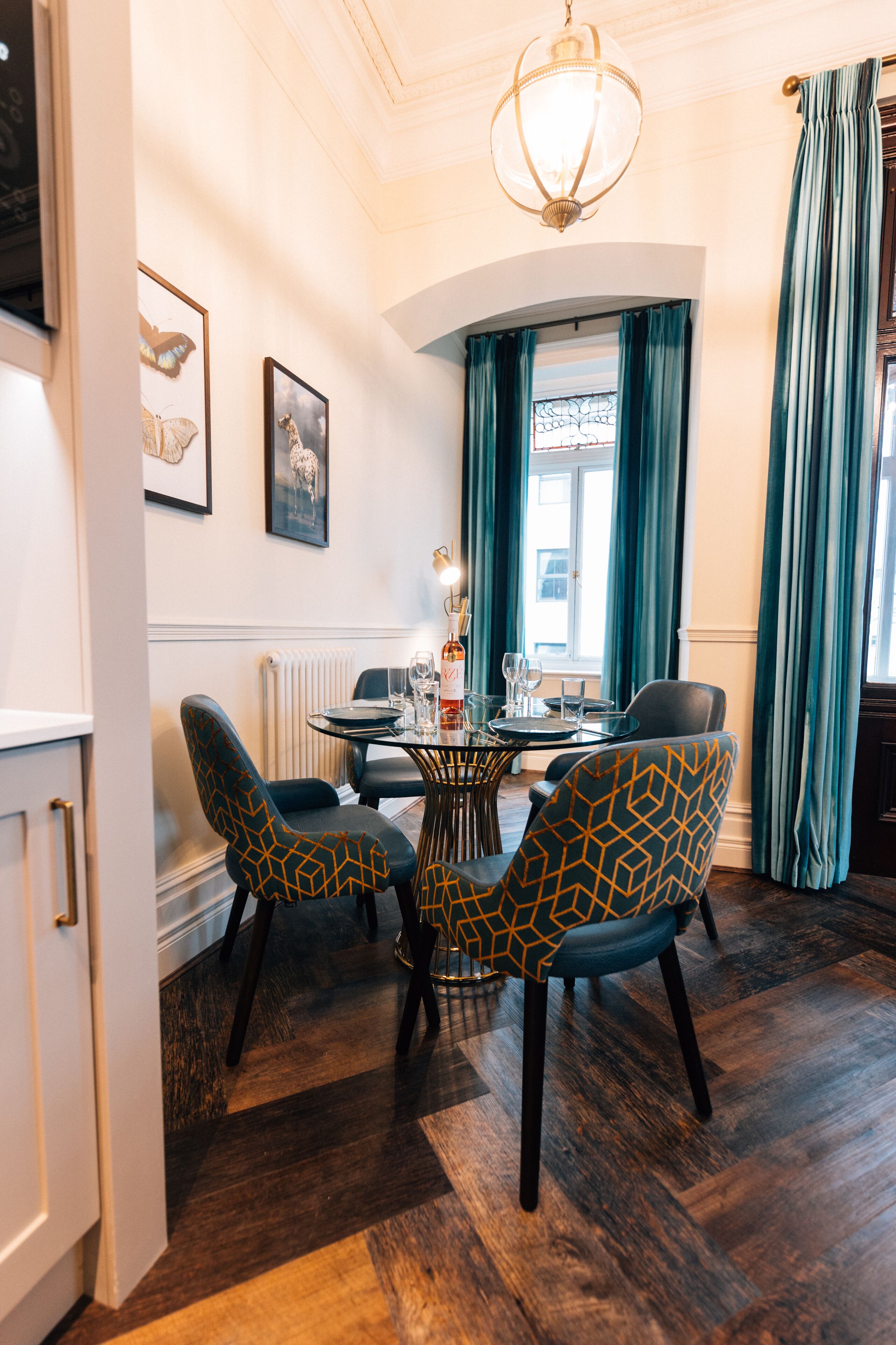 A dining area with a round table, chairs, and a chandelier.