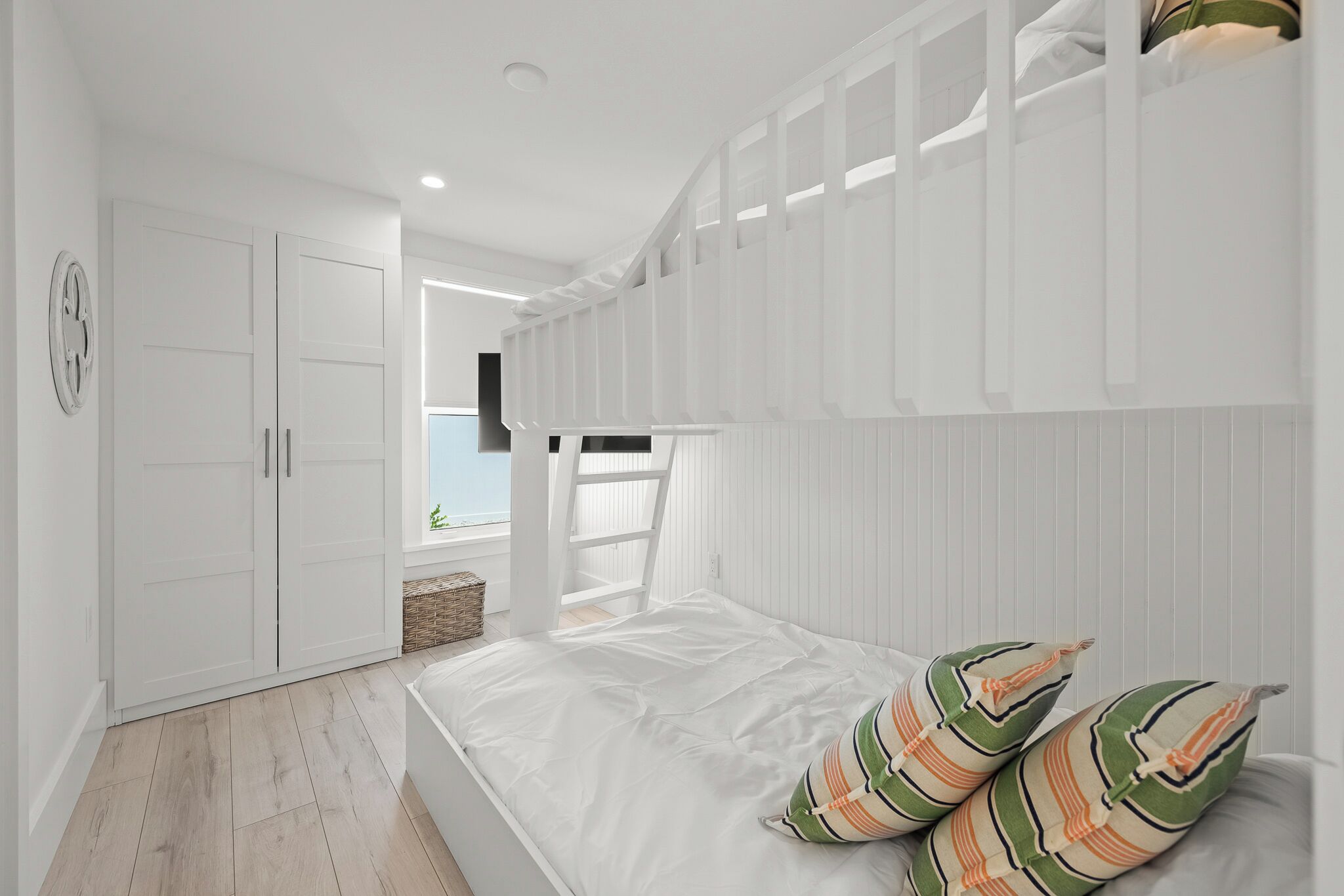 A bedroom with a bed, white wardrobe, and a view of the sea.
