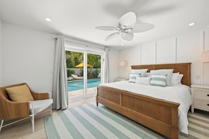Une chambre dotée d’un grand lit, d’une chaise, d’une table de chevet et offrant une vue sur une piscine extérieure.