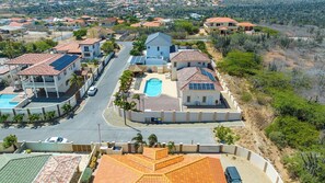 A residential area with multiple houses, a swimming pool, and a clear road.