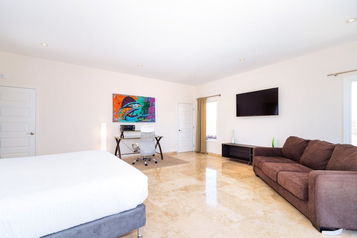 Un dormitorio moderno con una cama, un escritorio, un sofá y un televisor.