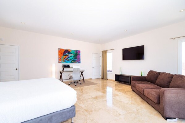 A modern bedroom with a bed, a desk, a couch, and a TV.