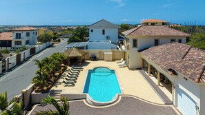 A residential property with a swimming pool, a covered outdoor area, and a view of the surrounding neighborhood.
