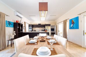 A modern dining area with a wooden table set for six, surrounded by white chairs.