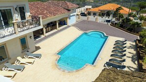 A swimming pool with lounge chairs, a covered patio, and a view of neighboring houses. - Stunning 4BR Pool Villa w Patio near Palm Beach (Noord)