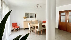 Een ruime eethoek met een houten tafel en stoelen, een lichtkleurige kast en een grote spiegel boven de tafel.
