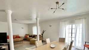 Een ruime woonkamer met een eettafel, banken en een televisie.