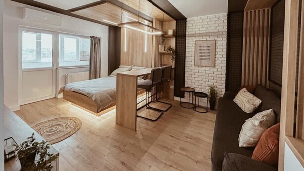 Une chambre de style loft moderne, avec un lit en mezzanine, un petit espace bureau et un coin salon confortable.