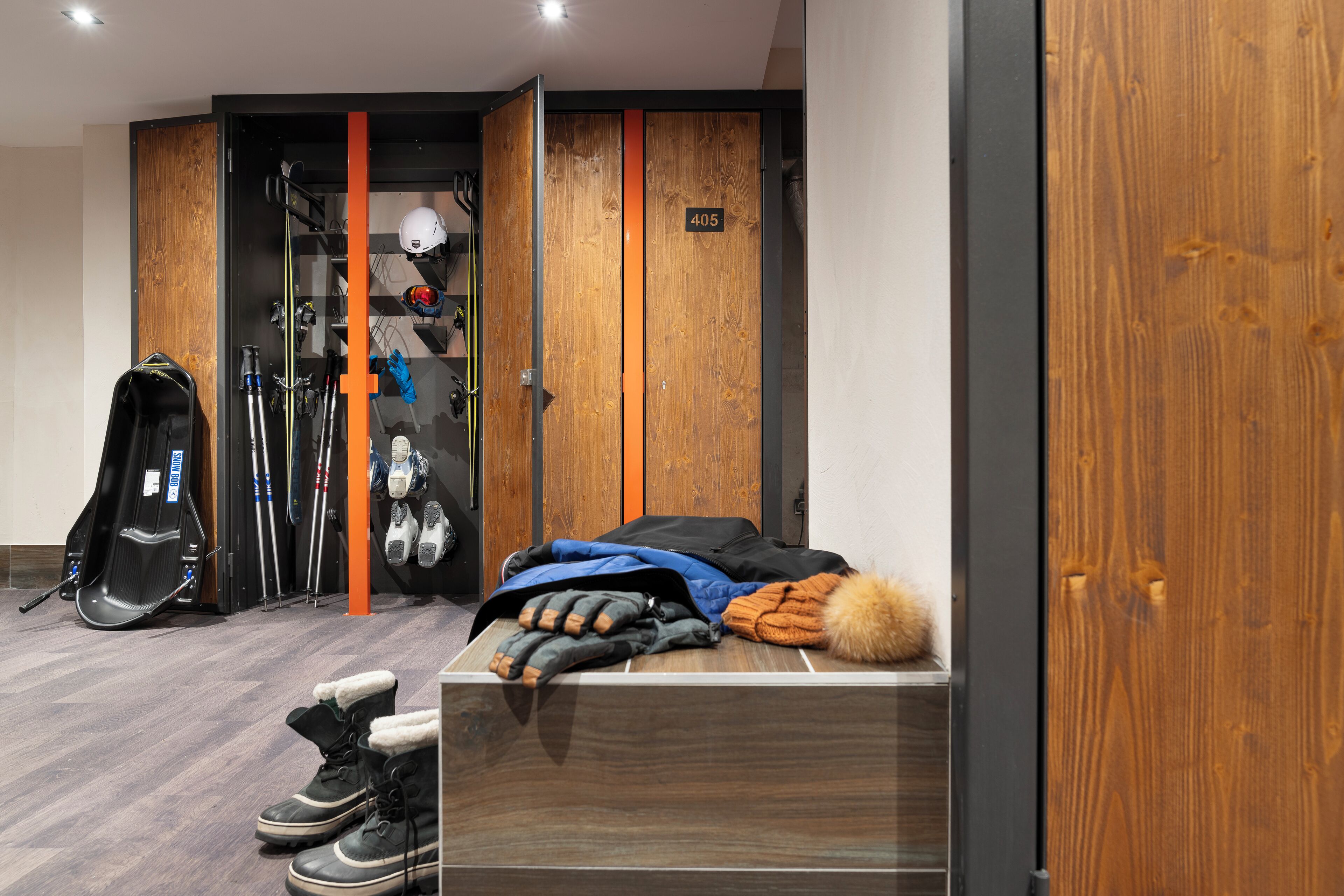 A hotel room with a bed, a ski bag, skis, and a helmet on the floor.
