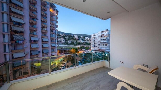 A balcony with a view of a cityscape, including high-rise buildings and a distant hill.