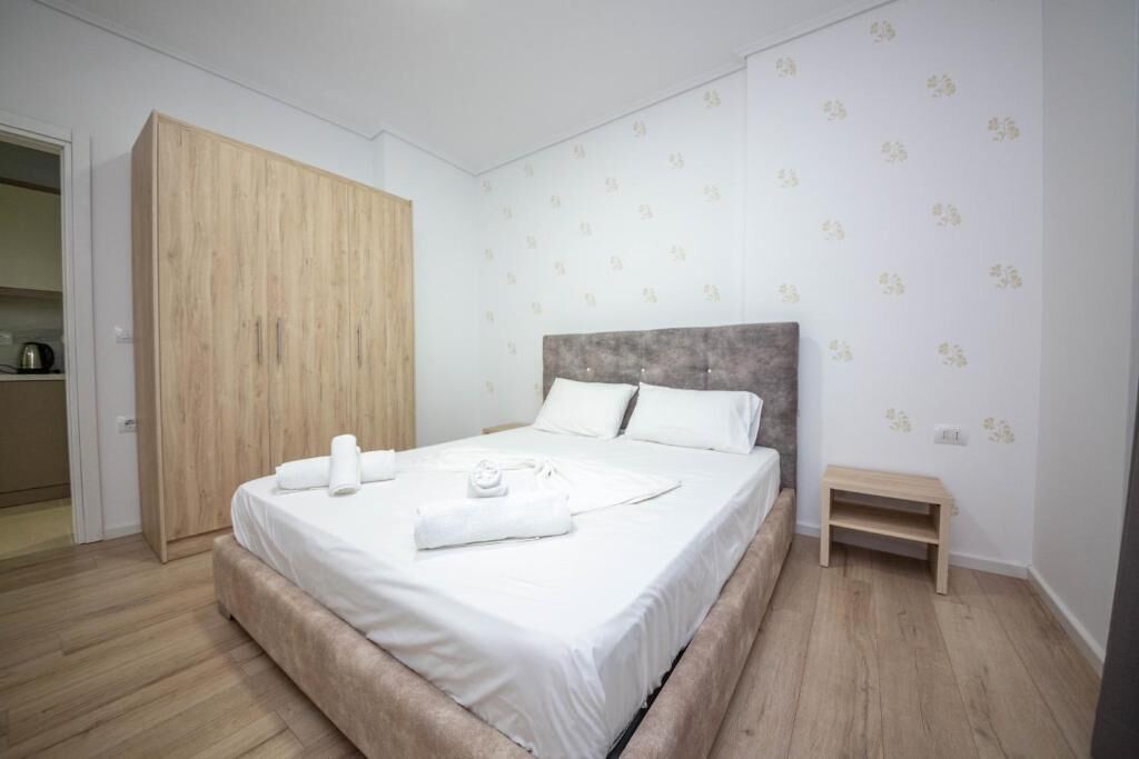 A neatly arranged bedroom with a large bed, a wardrobe, and a small bench.