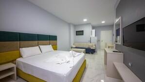 A hotel room with a large bed, a sofa, a desk, and a TV.