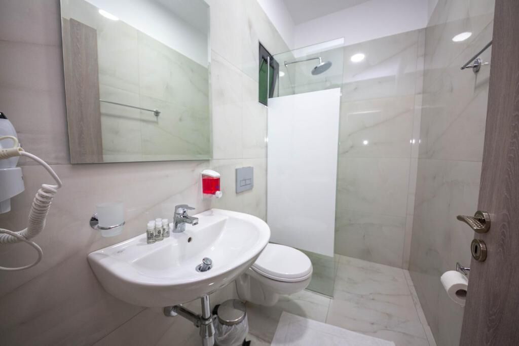A modern bathroom with a white sink, toilet, and glass-enclosed shower.