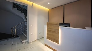 A modern reception area with a staircase, a wooden accent wall, and a reception desk.