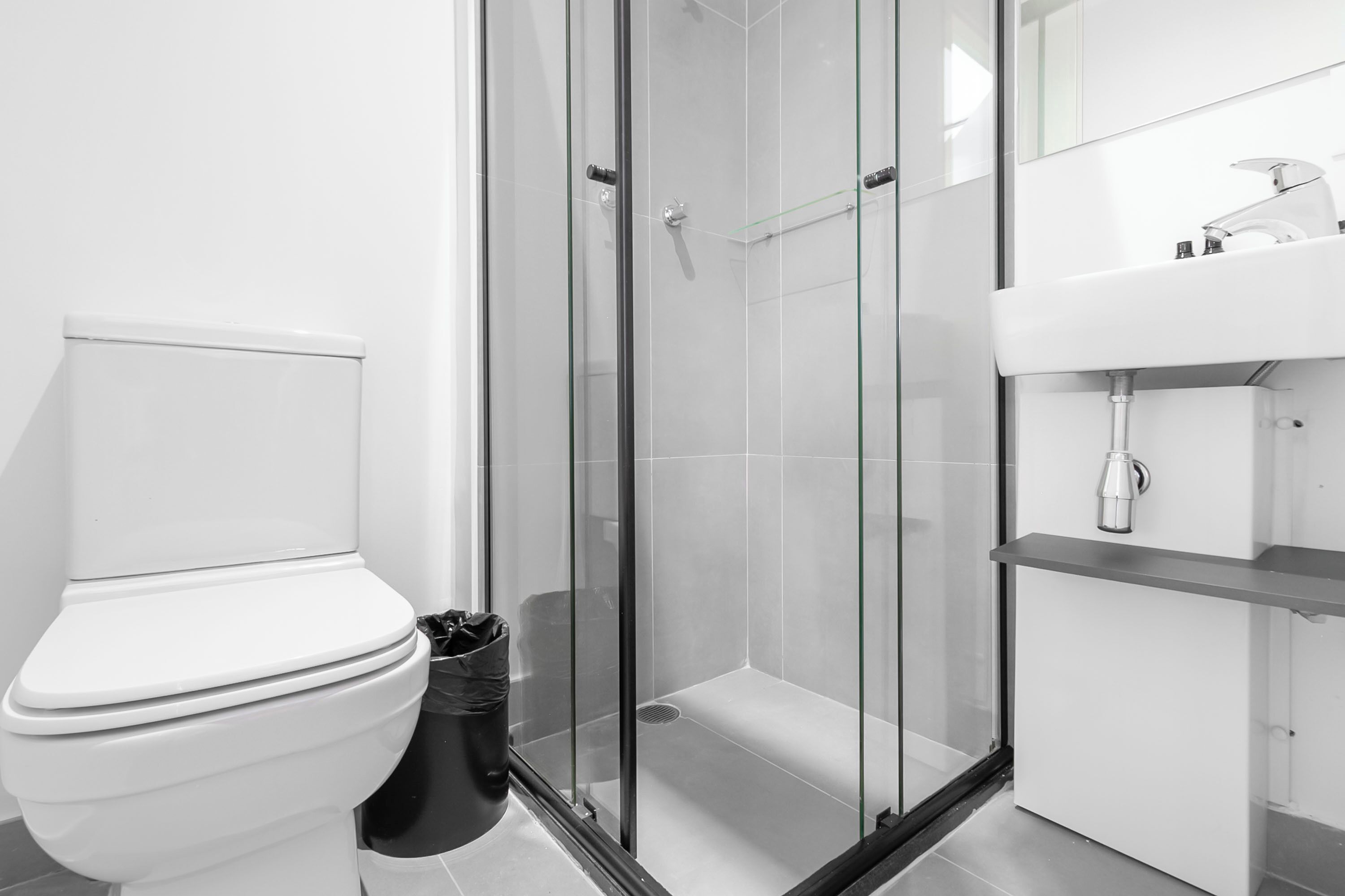 Uma casa de banho moderna com sanita, cabine de duche com vidro e lavatório.