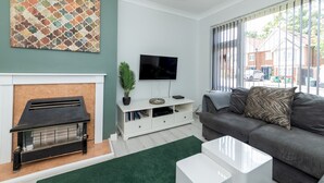 Una sala de estar con chimenea, televisor, sofá y una mesita de centro.