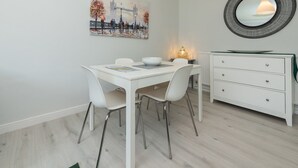 Un comedor moderno con una mesa blanca, sillas y un aparador blanco con cajones.