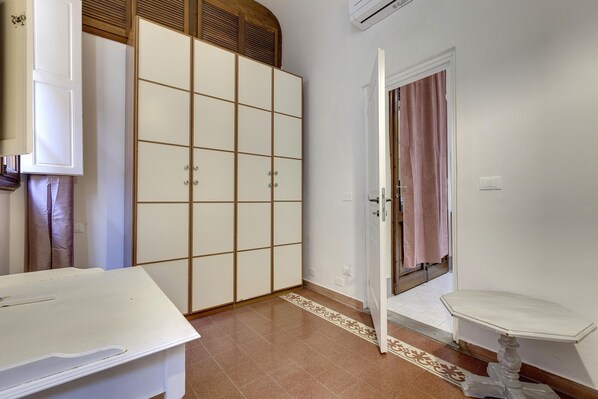 Une pièce comprenant un lit, une armoire, une petite table et une porte donnant sur une autre pièce.