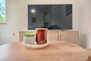 A round wooden table with a glass of amber liquid and a small potted plant on a white coaster. - A2- Luxury apt w big Balcony, 4 min Walk to Beach (Split)