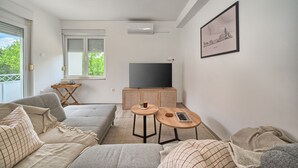 A modern living room with a sofa, a coffee table, a TV, and a framed picture on the wall. - A2- Luxury apt w big Balcony, 4 min Walk to Beach (Split)