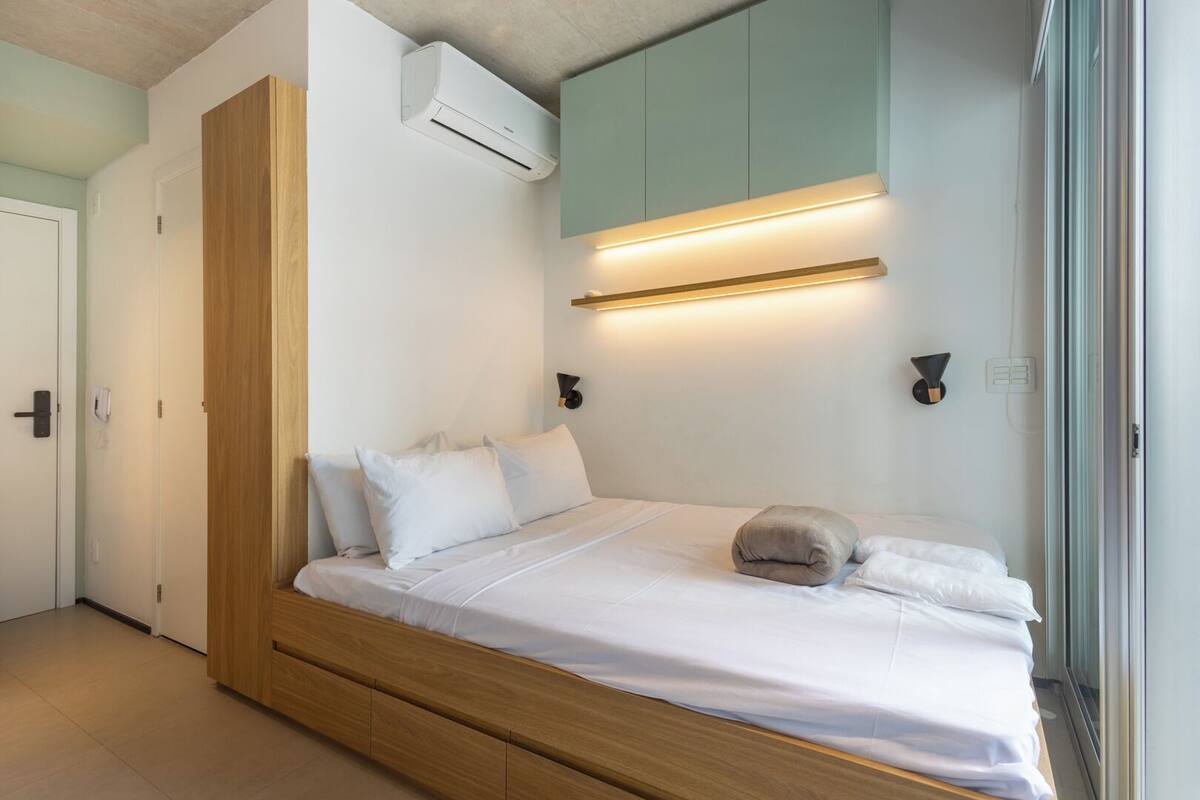 A modern bedroom with a built-in bed, wooden wardrobe, and an air conditioning unit.
