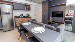 Una cocina moderna con refrigerador empotrado, armarios de madera y televisor de pantalla plana montado en la pared.