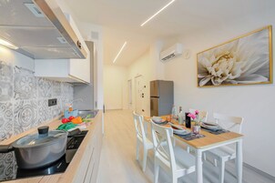 Una cocina moderna con estufa, una mesa de comedor con sillas y un cuadro grande de flores en la pared.