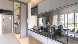 A modern kitchen with stainless steel appliances, a built-in microwave, and a large window offering a view of the city. - 360 VN Faria Lima (São Paulo)