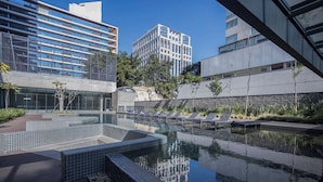 A modern outdoor pool area with lounge chairs and a view of surrounding buildings. - 360 VN Faria Lima (São Paulo)