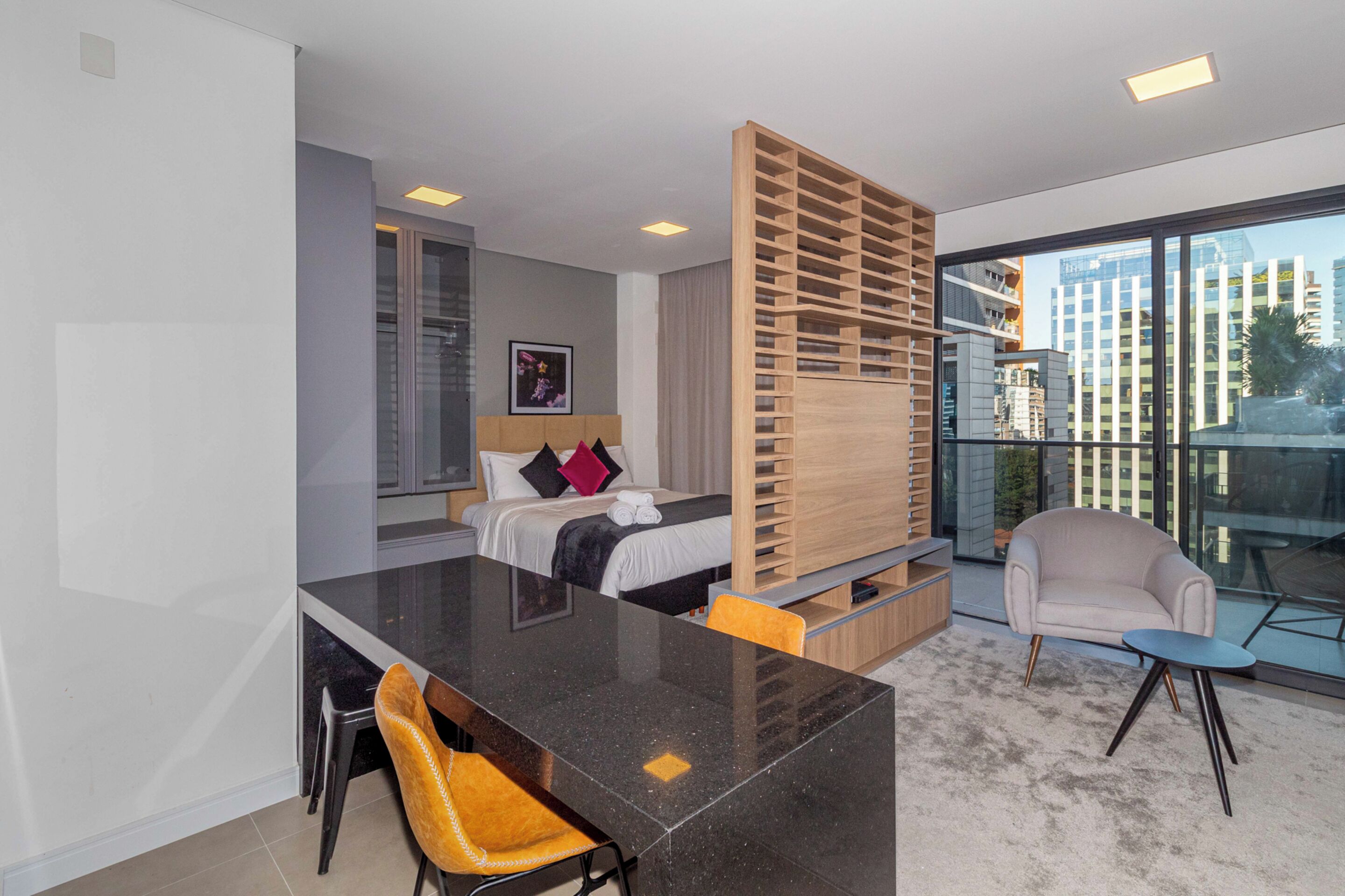 Een moderne hotelkamer met een groot bed, een bureau, een stoel en een balkon met uitzicht op de stad.