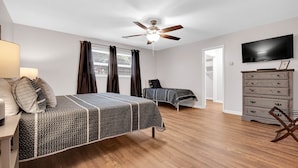 A bedroom with a bed, a ceiling fan, a TV, a dresser, and a chair. - Fantastic for Extended Stays & Work Crews- 10 beds, 5 bedrooms, 2.5 baths (Warner Robins)
