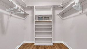 A walk-in closet with white shelving, a wooden floor, and a white ceiling. - Fantastic for Extended Stays & Work Crews- 10 beds, 5 bedrooms, 2.5 baths (Warner Robins)