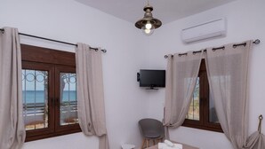 A room with two beds, a TV, and a view of the sea. - Atalanti Seaside Junior Suites (Viannos)