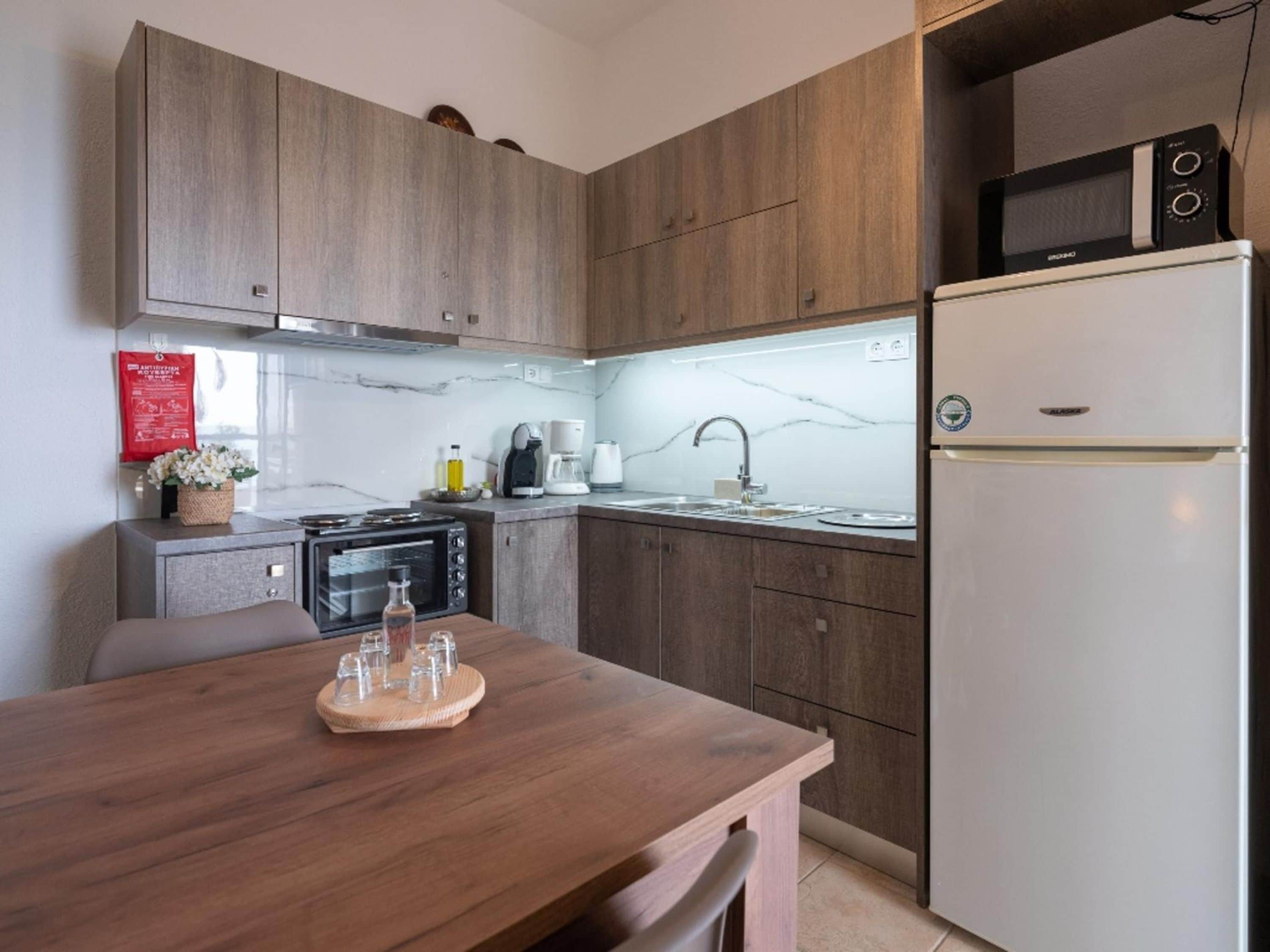 Una cucina moderna con mobili in legno, forno integrato, microonde e frigorifero.