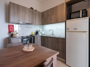 A modern kitchen with wooden cabinets, a white refrigerator, a microwave, a stove, and a sink.
