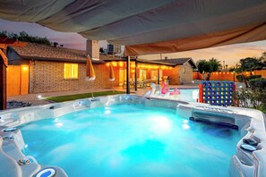 A hot tub area with a covered patio, a brick house, and a pool in the background. - Sleeps 20! Pool, Basketball, Golf  Dream Resort (Scottsdale)