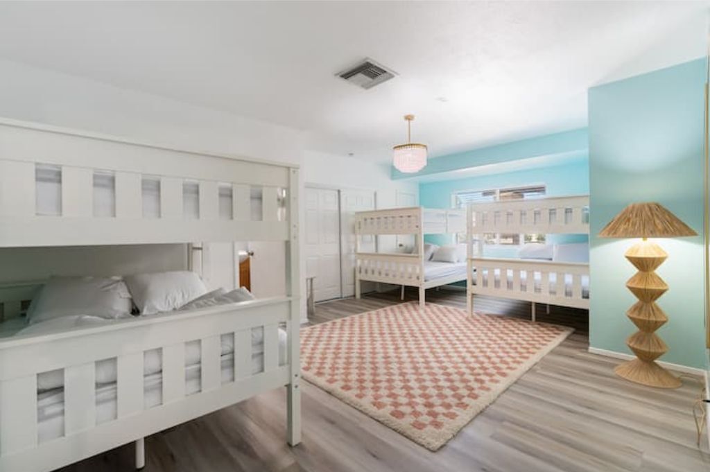 A children's room with bunk beds, a patterned rug, and a lamp.