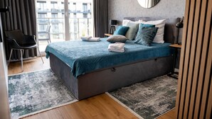 A modern bedroom with a large bed, a chair, and a view of the outside. - Apartment with river view, sauna and indoor pool (Dziwnow)