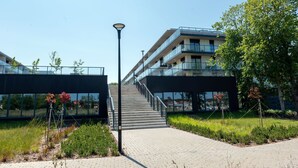 A modern building with a glass facade, outdoor stairs, and a pathway. - Apartment with river view, sauna and indoor pool (Dziwnow)