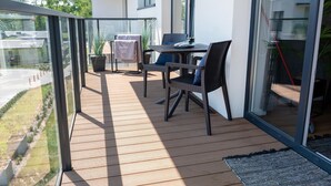 A balcony with a table and chairs, a potted plant, and a view of the surrounding area. - Apartment with river view, sauna and indoor pool (Dziwnow)