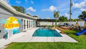 Um quintal com piscina, cadeiras de descanso e um escorrega.