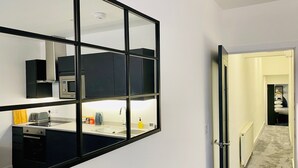 Cozinha moderna com um espelho grande, eletrodomésticos embutidos e vista para o quarto vizinho.