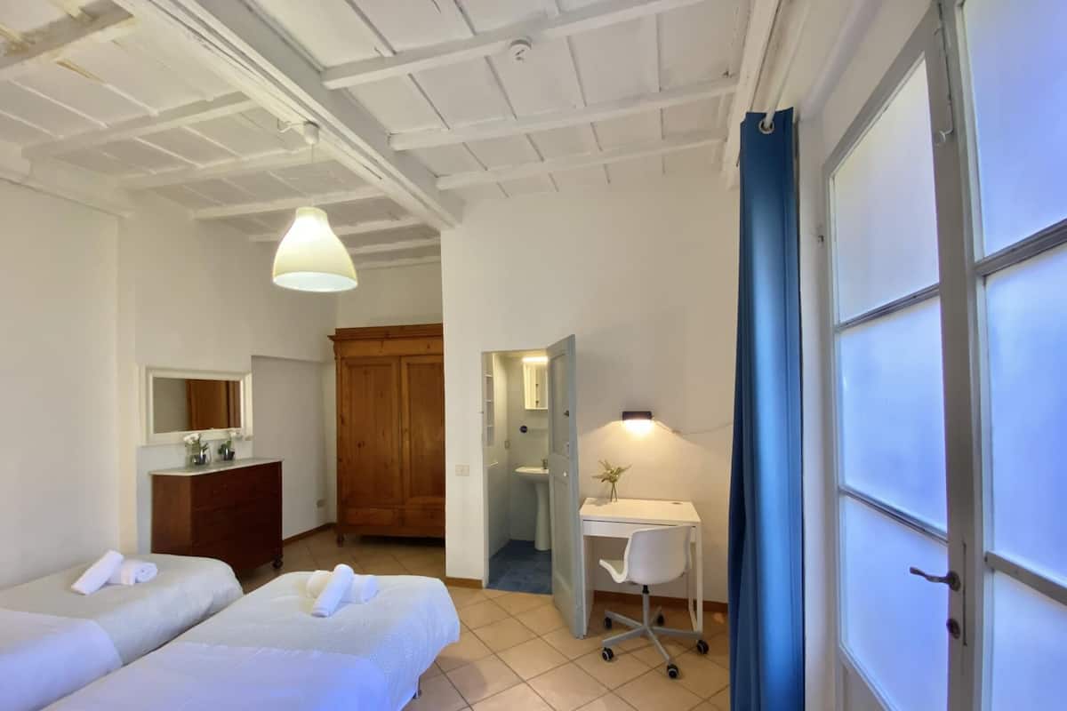 Habitación de hotel con dos camas, un escritorio con silla, baño y armario.