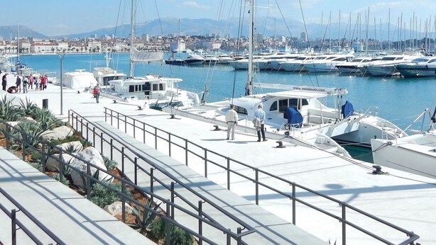 A marina with boats docked, a cityscape in the background, and a pedestrian walkway with railings. - A 2 Spacious apt w big Balcony,4 min Walk to Beach (Split)