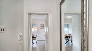 A hallway with a telephone, a dining area with chairs and a table, and a mirror with a decorative frame. - A 2 Spacious apt w big Balcony,4 min Walk to Beach (Split)