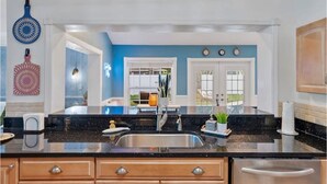 Una cocina moderna con encimera de granito negro, lavabo de acero inoxidable y armarios de madera.