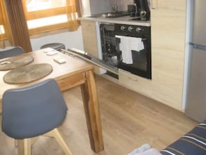 A compact kitchen with a wooden table, chairs, and a built-in oven. - Wine studio (Gevrey-Chambertin)