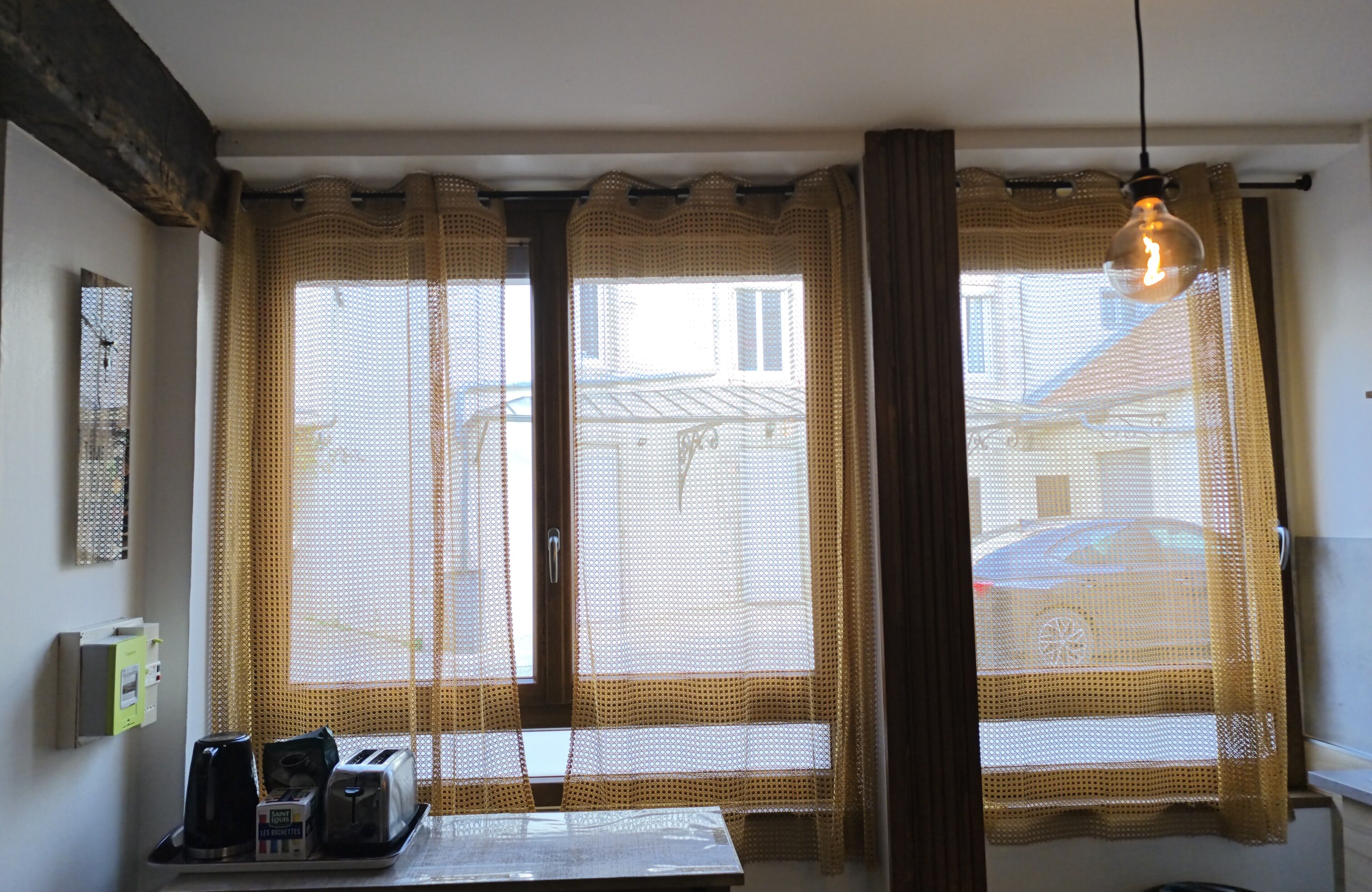 A room with a window, a table with a tray of items, and a hanging light fixture.