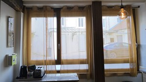 Et værelse med et vindue, et bord med en bakke ting og en hængende lampe.