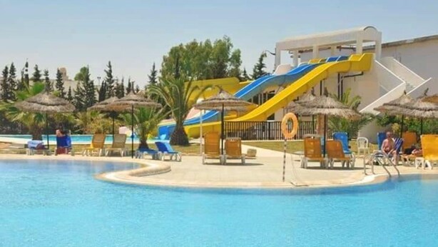 A swimming pool with a water slide, lounge chairs, and umbrellas. - Yasmine Beach - Families and Couples (Hammamet)